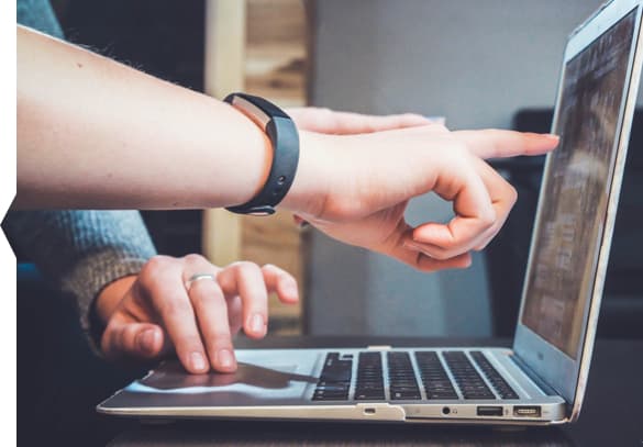 Multiple hands pointing to a laptop screen