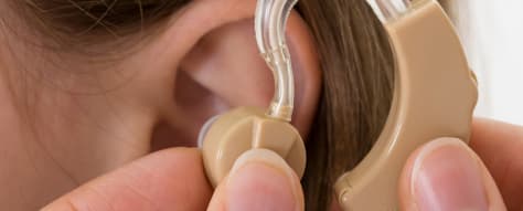Healthcare professional fitting a hearing aid on a patient