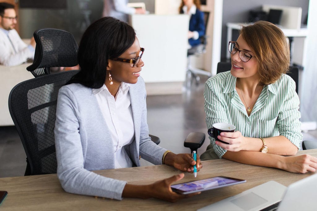 Two female co-workers meeting at a desk