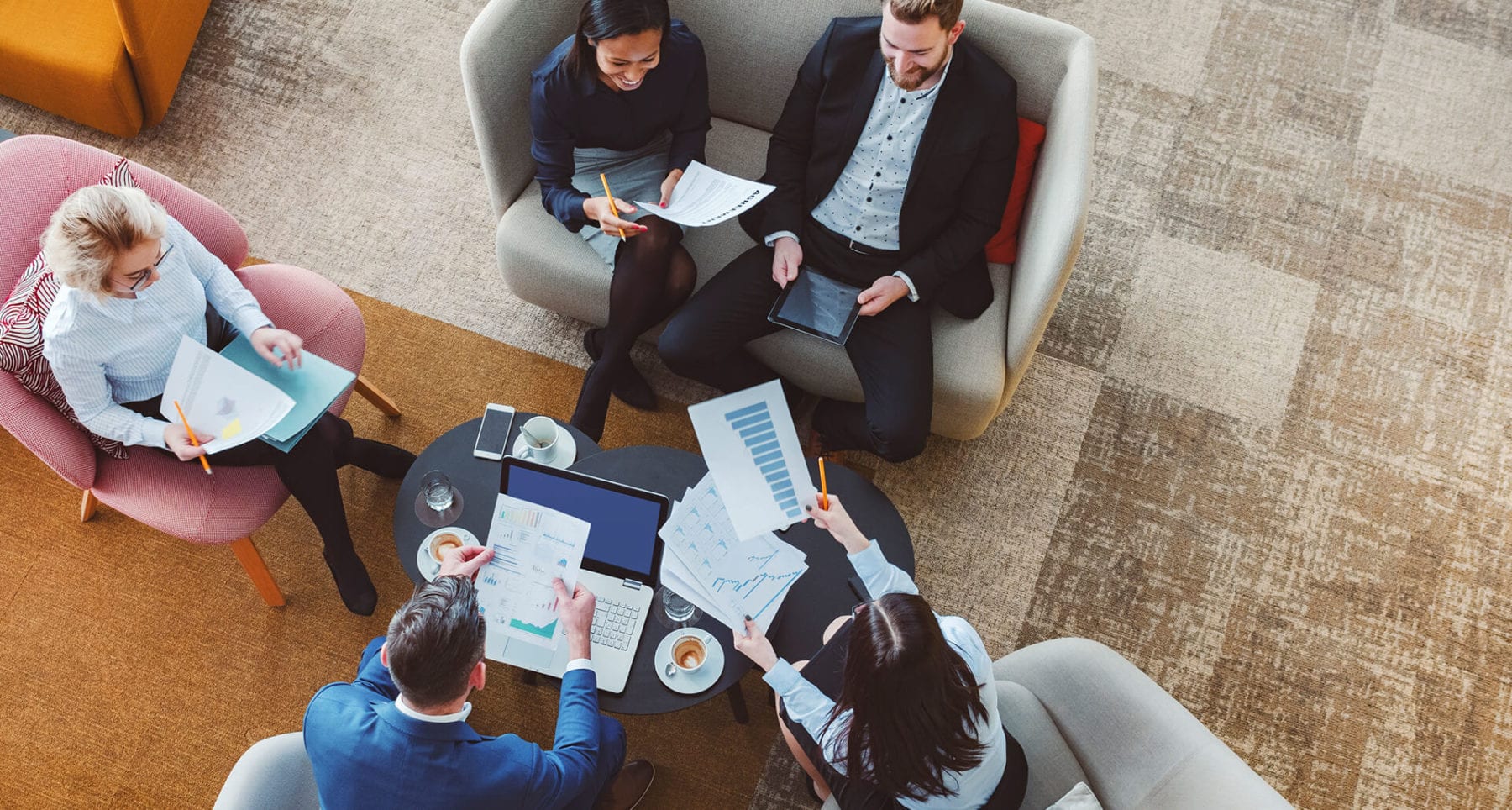 Five colleagues reviewing graphs in an informal office meeting