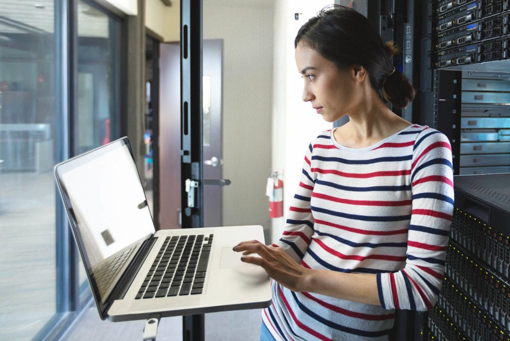 Female professional holding her laptop is a server room