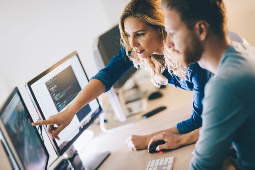 Two co-workers discussing work on a desktop