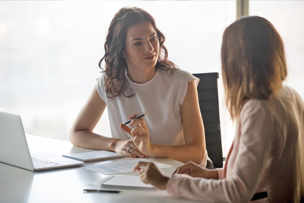 Two female co-workers meeting at a desk