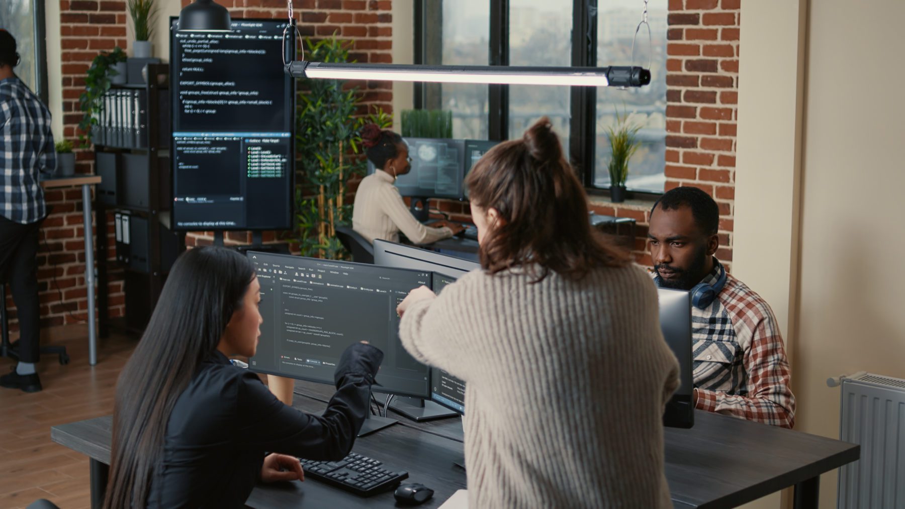 Software programer pointing pencil at source code on computer screen explaining algorithm to coworker