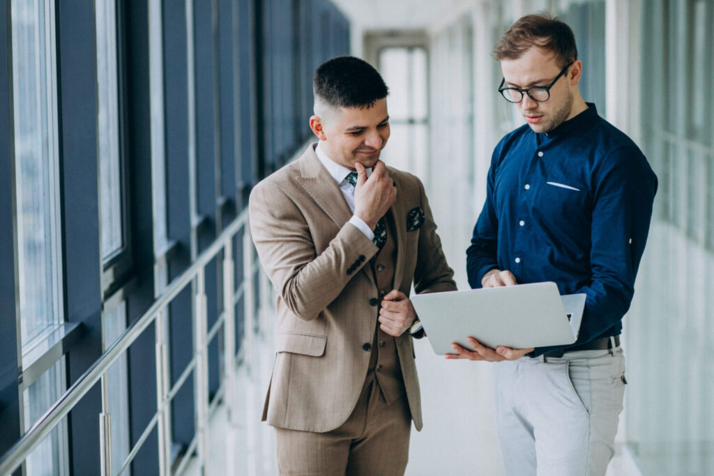 Two male colleagues at the office,standing with laptop