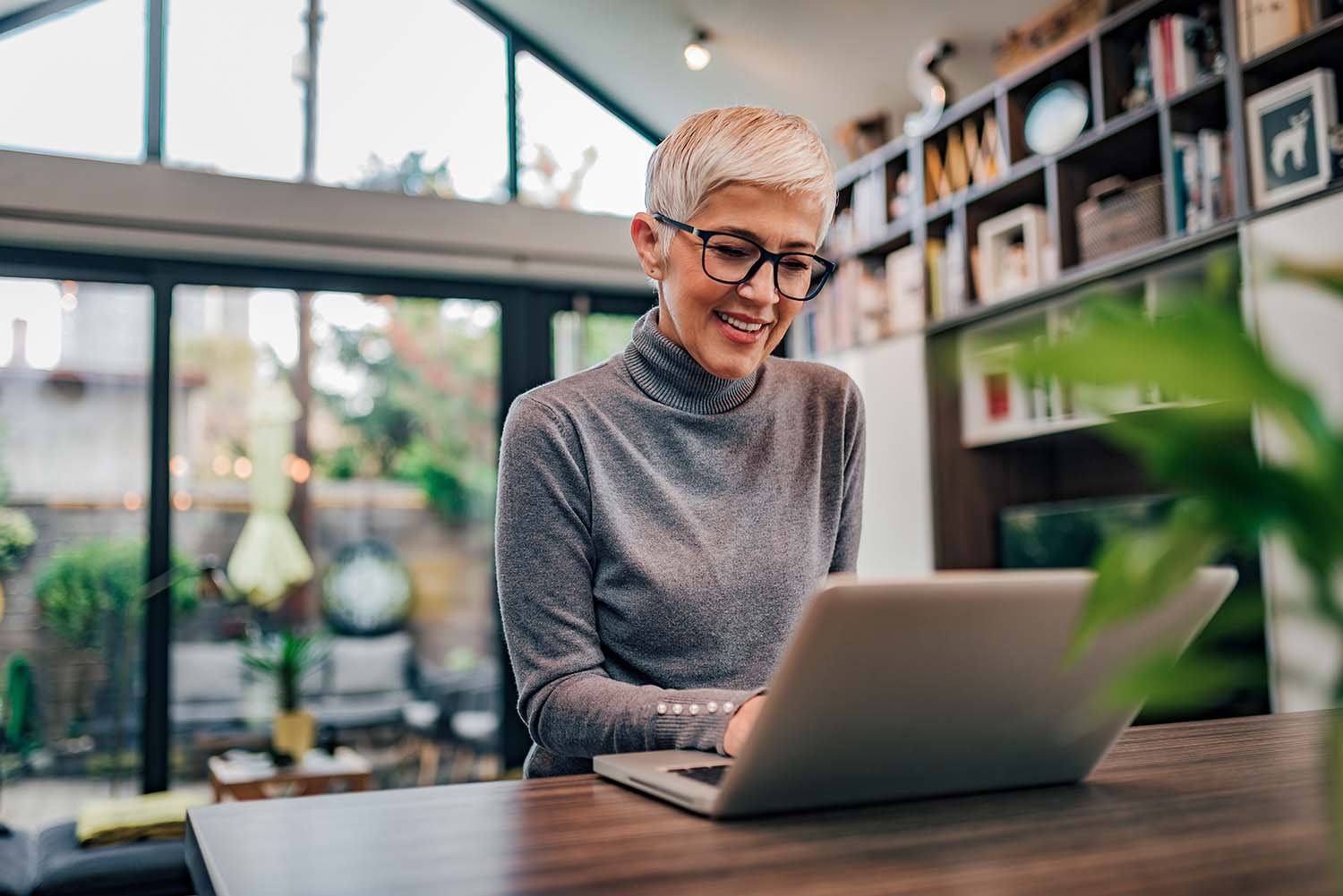 Portrait-of-a-cheerful-mature-businesswoman-working-on-laptop-at-home-office